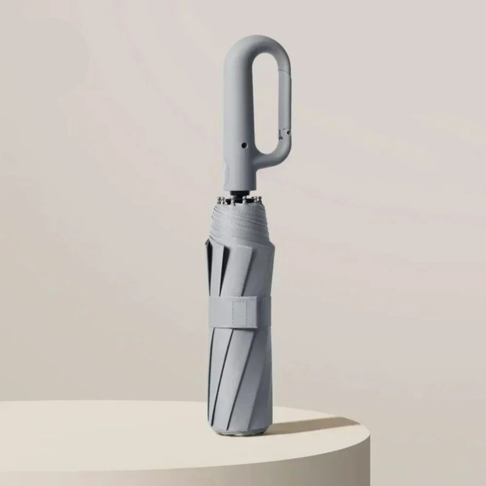 Grey umbrella with a minimalist design on a light beige background, featuring the UPF50+ logo.