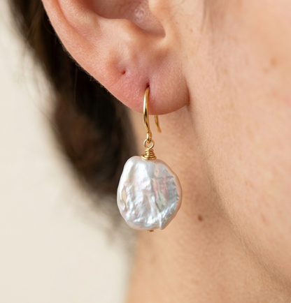 Pearl earring worn on an ear with a neutral background