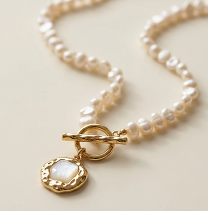 Pearl necklace with a gold clasp on a light background