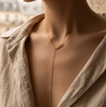 Woman wearing a delicate Veruccia gold necklace with a blurred cityscape background