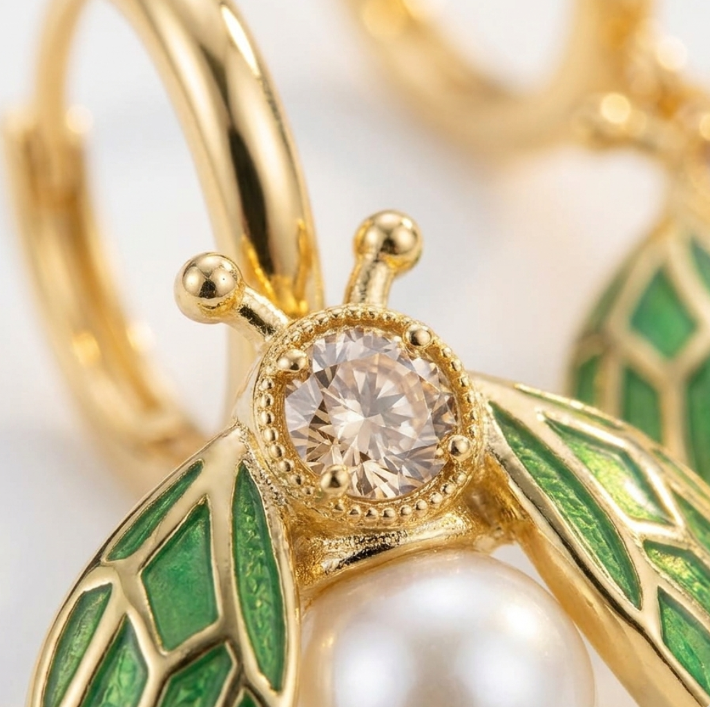 Gold earring with green leaves and a pearl on a white background