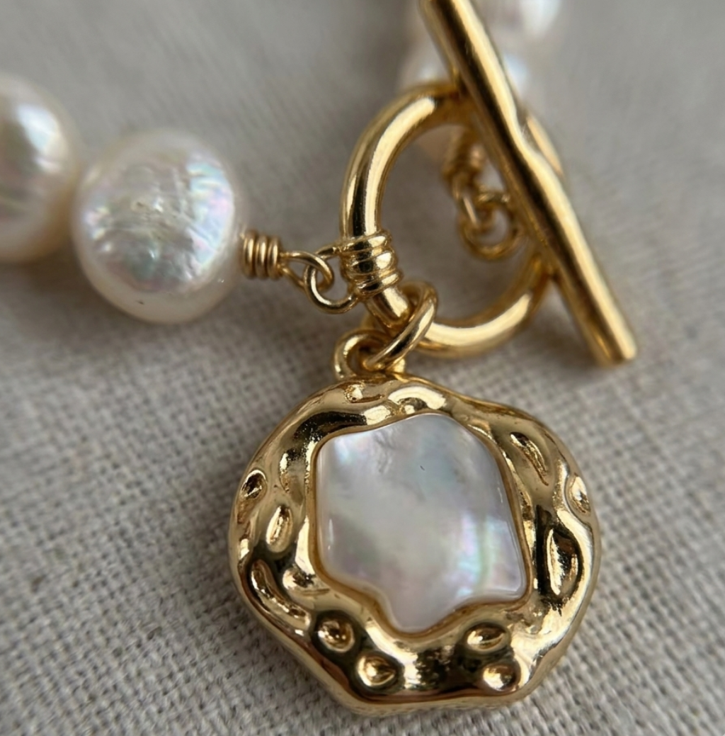 Pearl bracelet with a gold clasp on a light fabric background