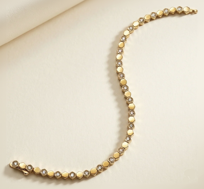 Gold tennis bracelet with small diamonds on a beige background