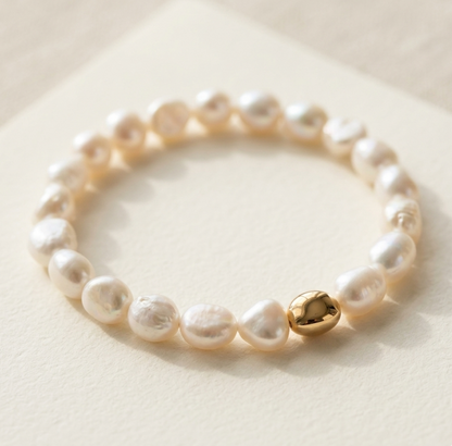 Pearl bracelet with a golden bead on a light background