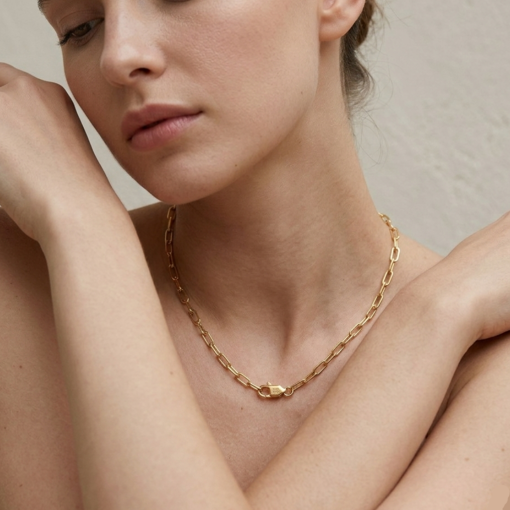 Woman wearing a gold chain necklace against a neutral background