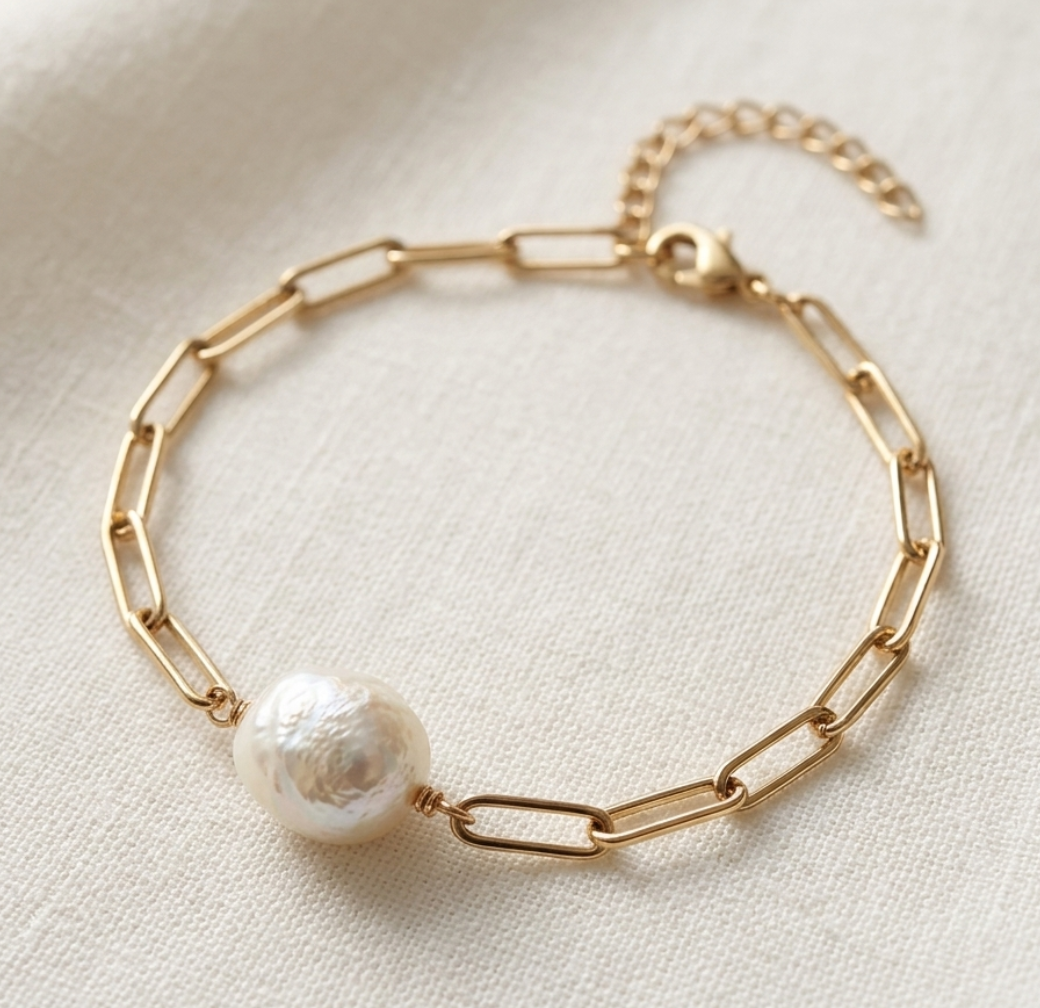 Gold bracelet with a pearl on a light fabric background