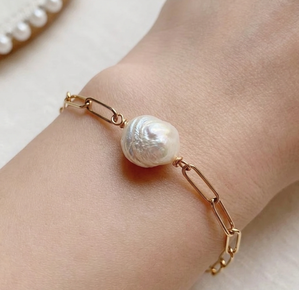 Veruccia bracelet with a pearl on a wrist against a neutral background