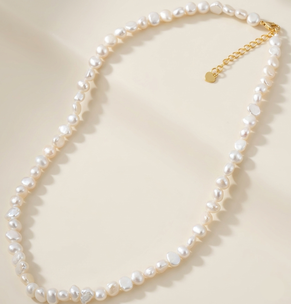 Pearl necklace with a gold chain on a light beige background