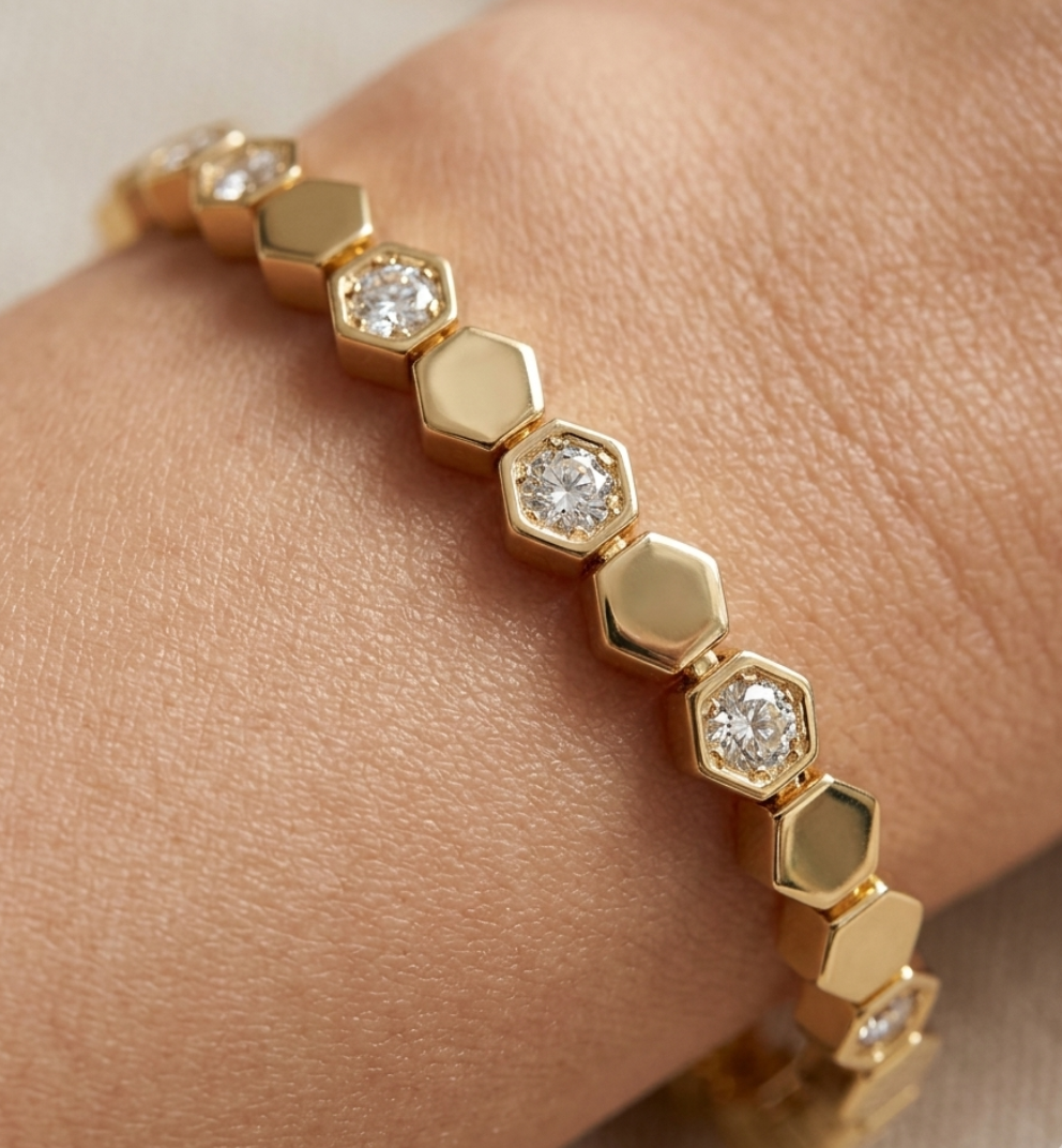 Gold bracelet with hexagonal beads on a wrist against a neutral background