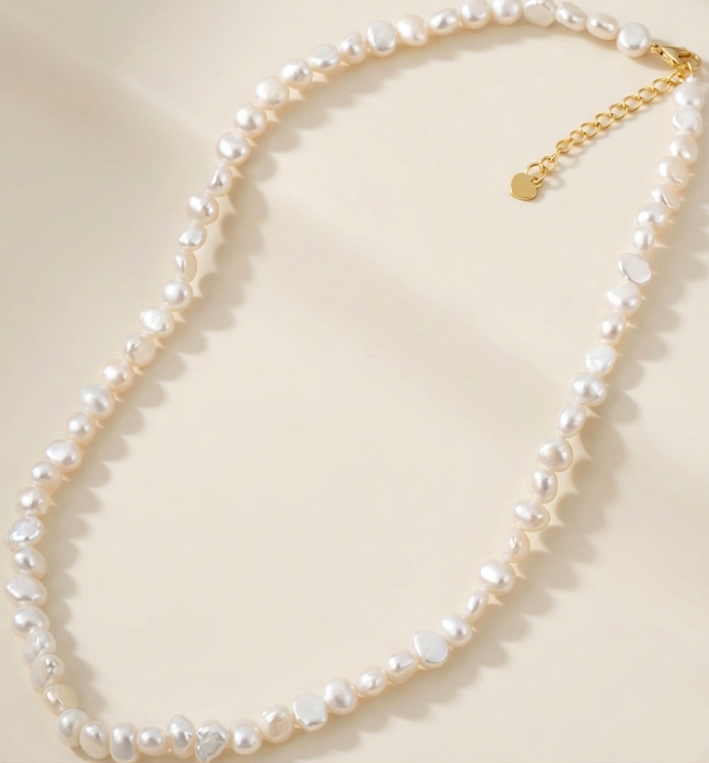 Pearl necklace with a gold chain on a light beige background