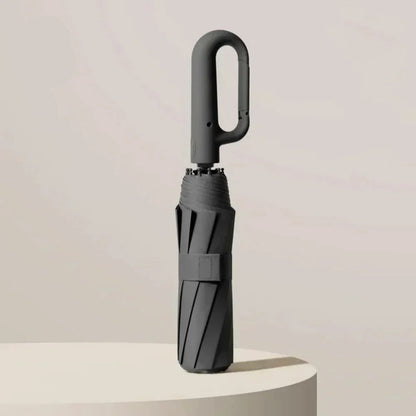 Black umbrella with UPF50+ label on a light beige background
