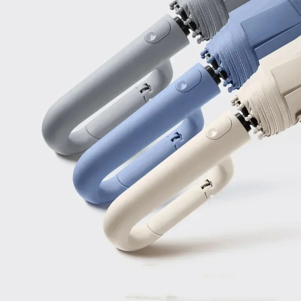 Three umbrellas in gray, blue, and beige on a light gray background